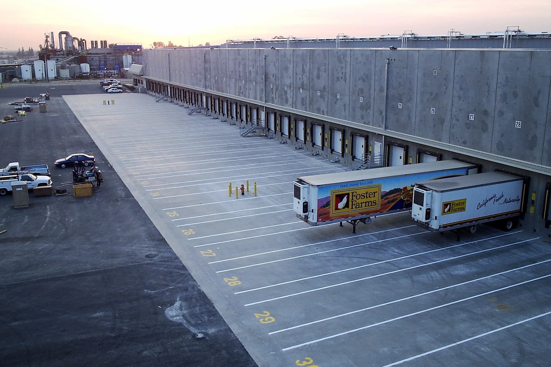 Elevated view of Foster Farms refrigerated truck bays with loading docks, distribution warehouse, trailer parking, and adjacent food processing facility.