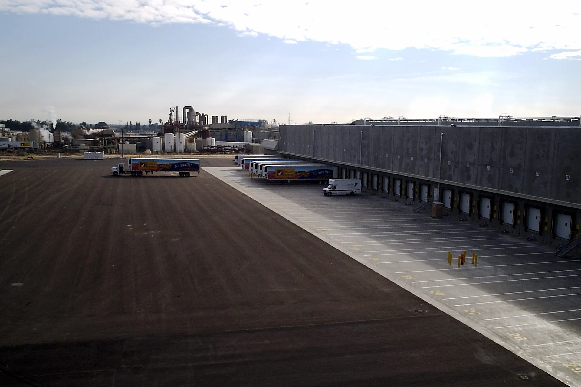 Loading dock operations at the Foster Farms National Chicken Distribution Center with refrigerated trailers, truck bays, and adjacent food processing facility.