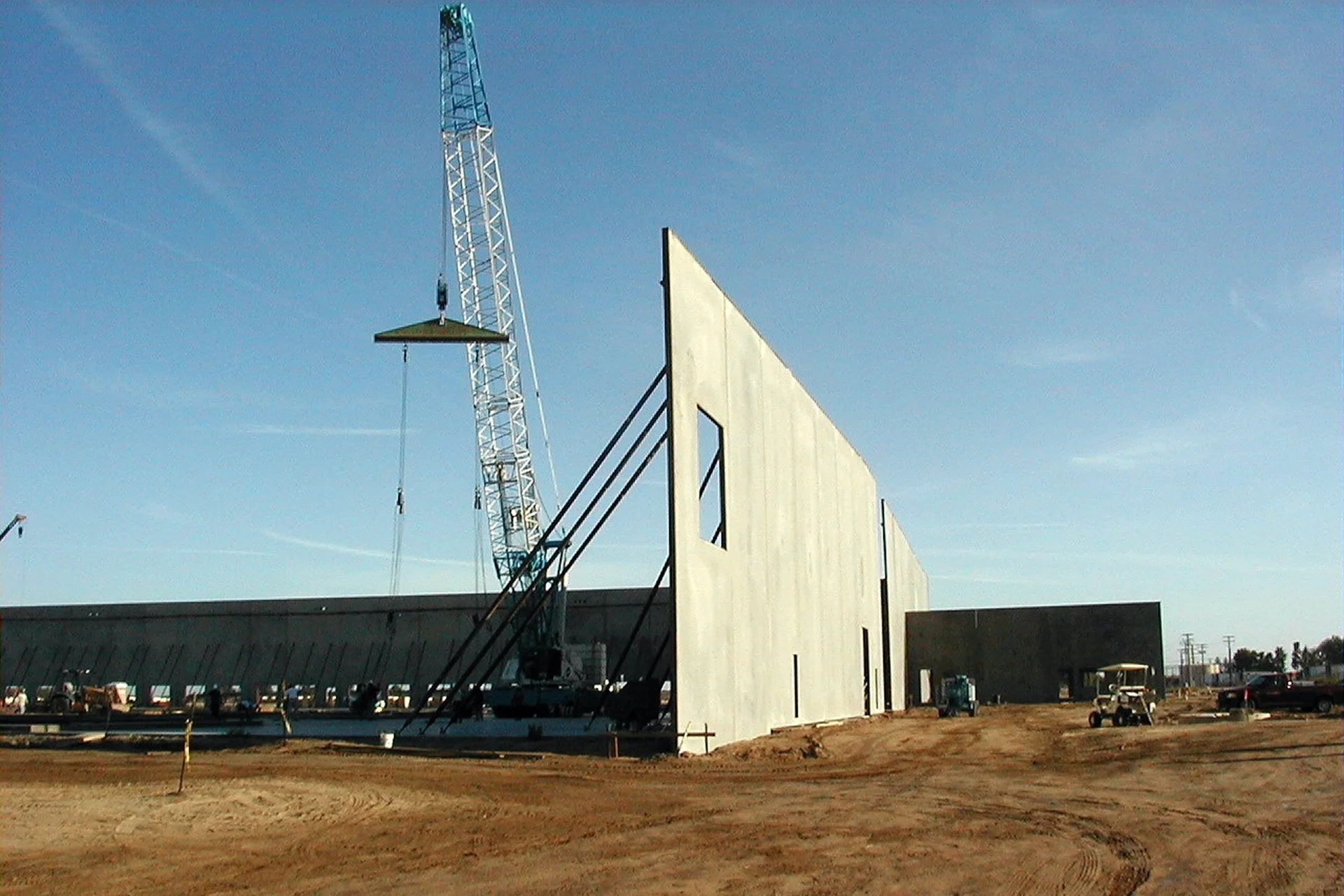 Construction of the Foster Farms National Chicken Distribution Center showing precast concrete wall panels being installed with a crane at the warehouse site.