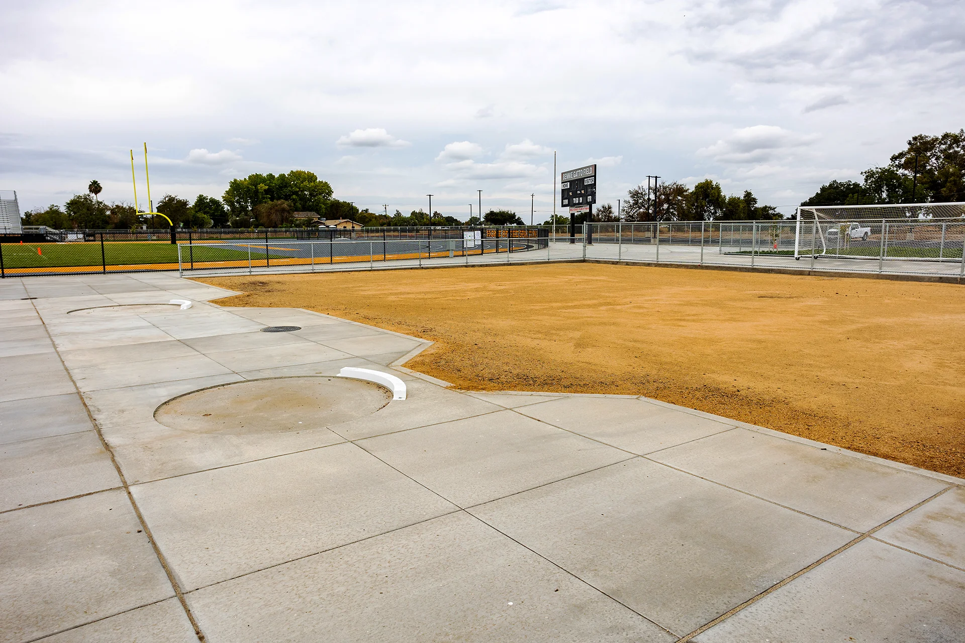 Concrete shot put and discus throwing rings with white toe boards at the Lathrop High School athletic facility.