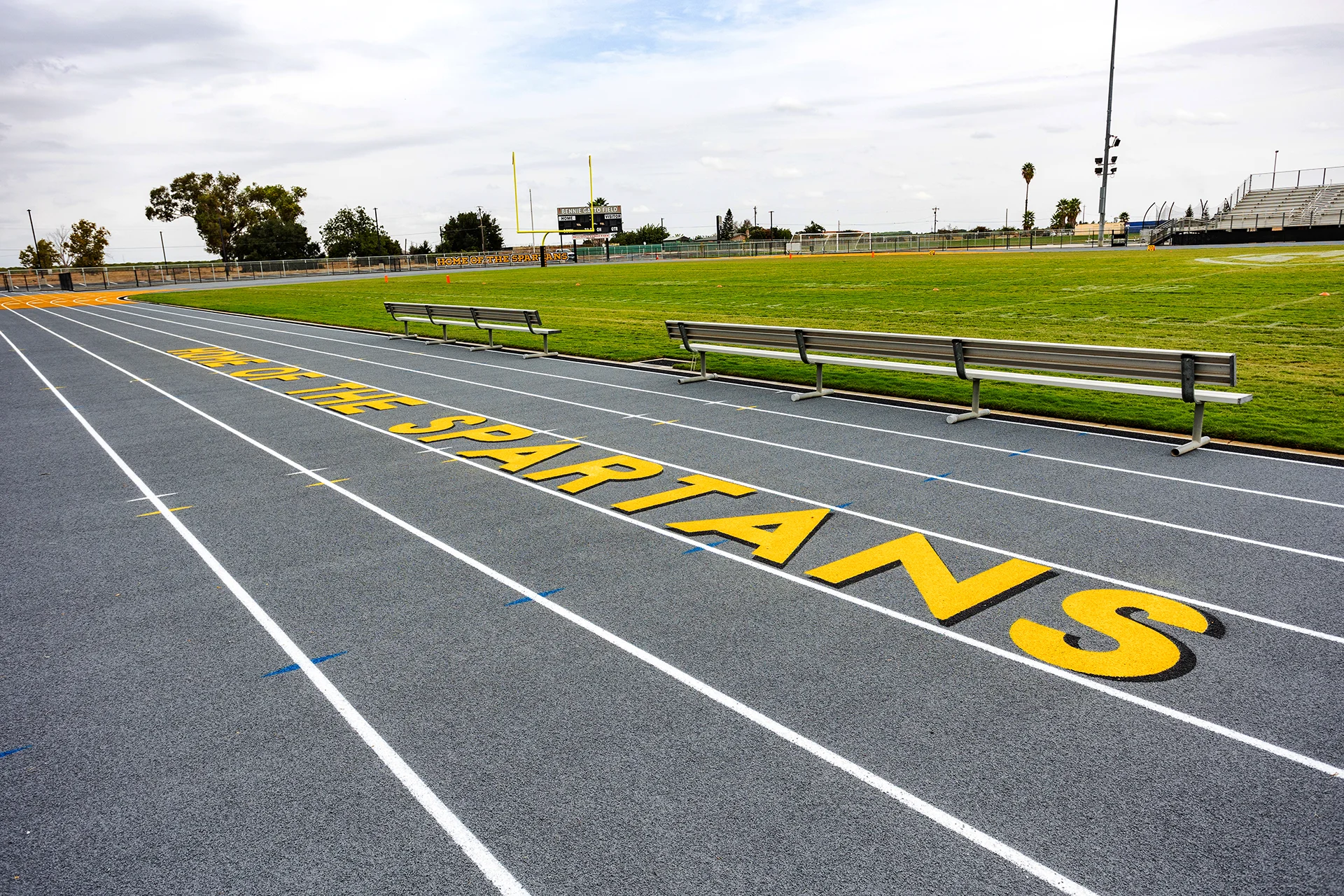 Lathrop High School running track featuring Spartans branding, field seating, football field, scoreboard, and goalposts.