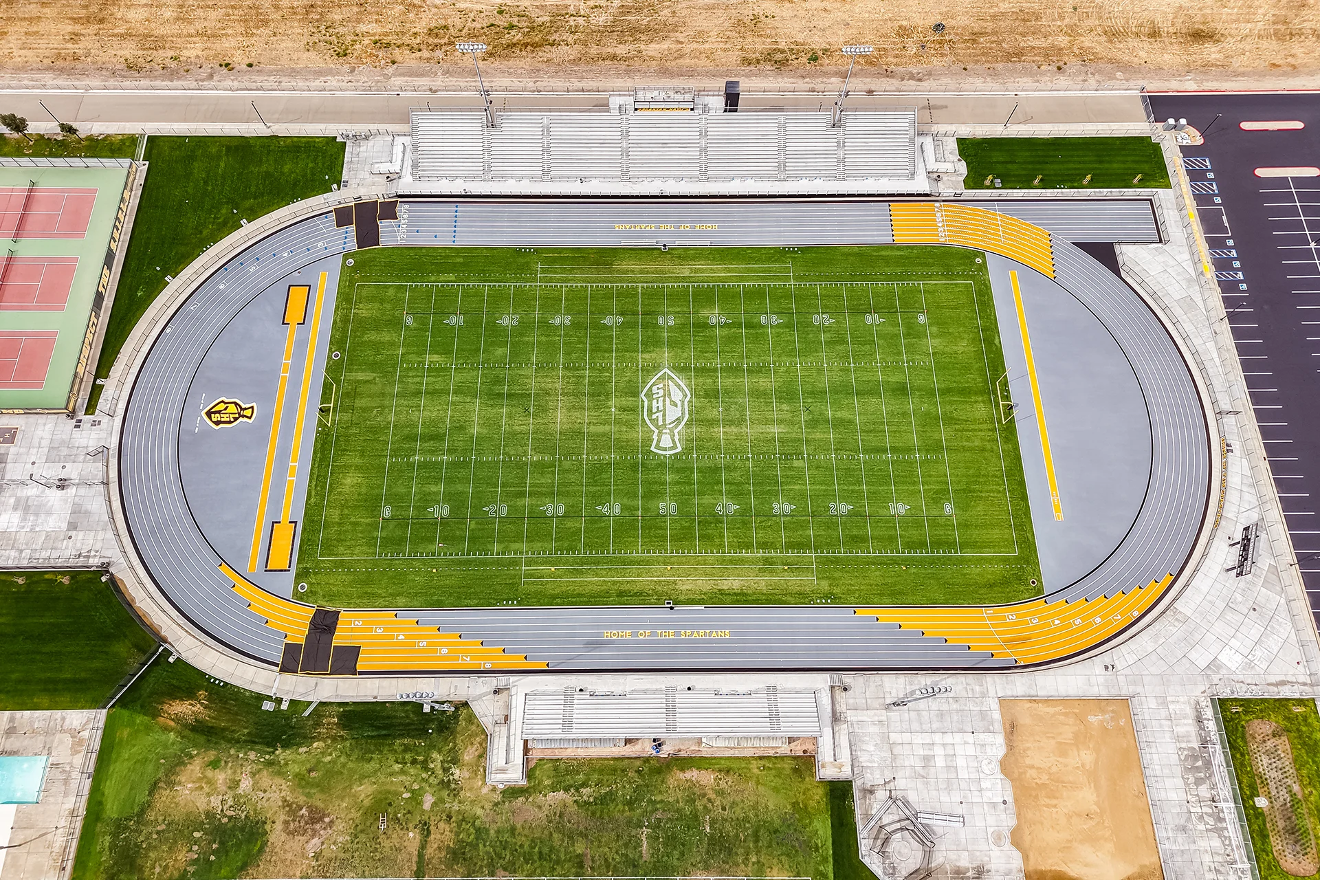 A high-angle drone photograph of the complete Lathrop High School stadium complex, including the football field, running track, bleachers, and nearby buildings.
