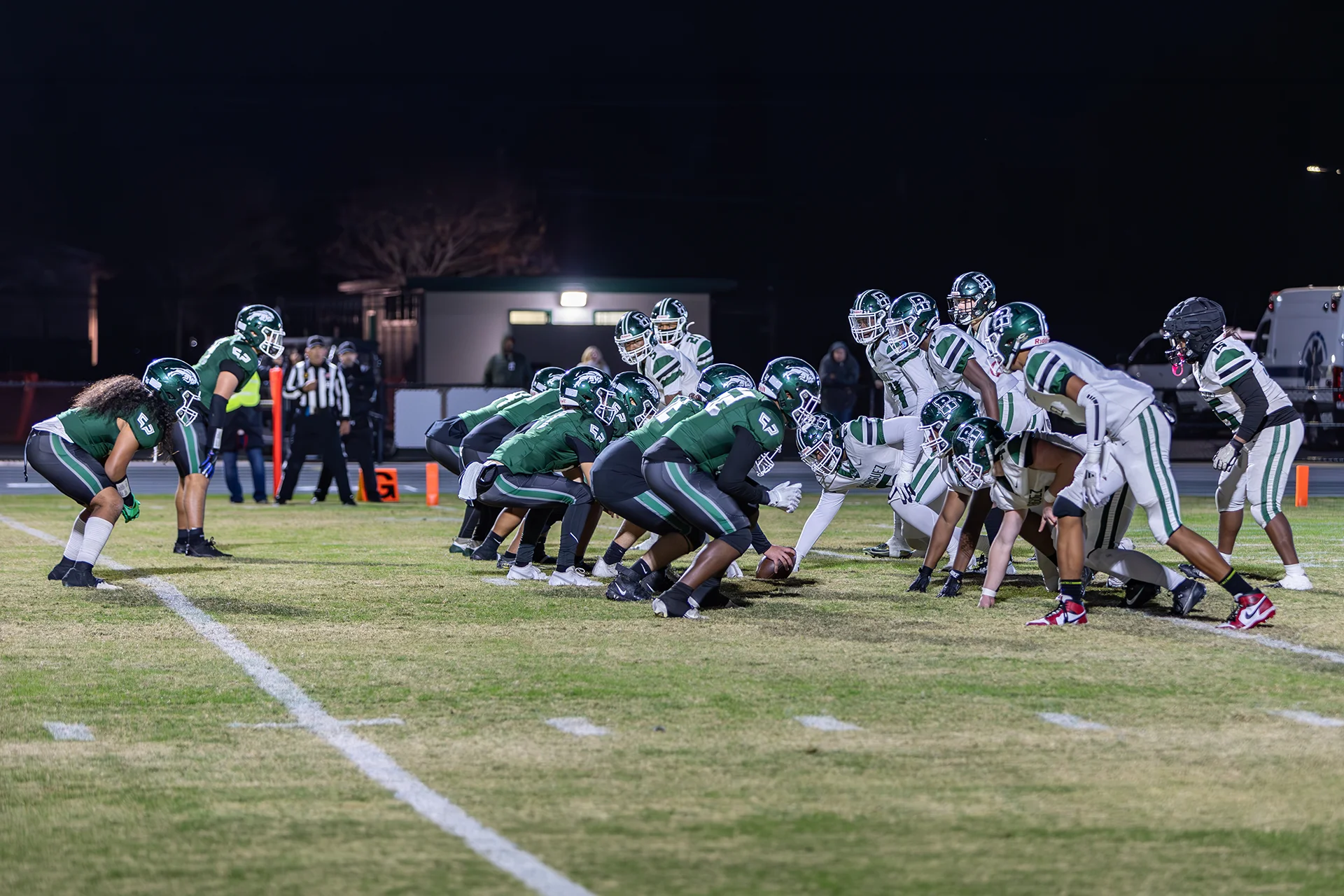 Manteca High School football players line up at the line of scrimmage during a nighttime game on the renovated athletic field.