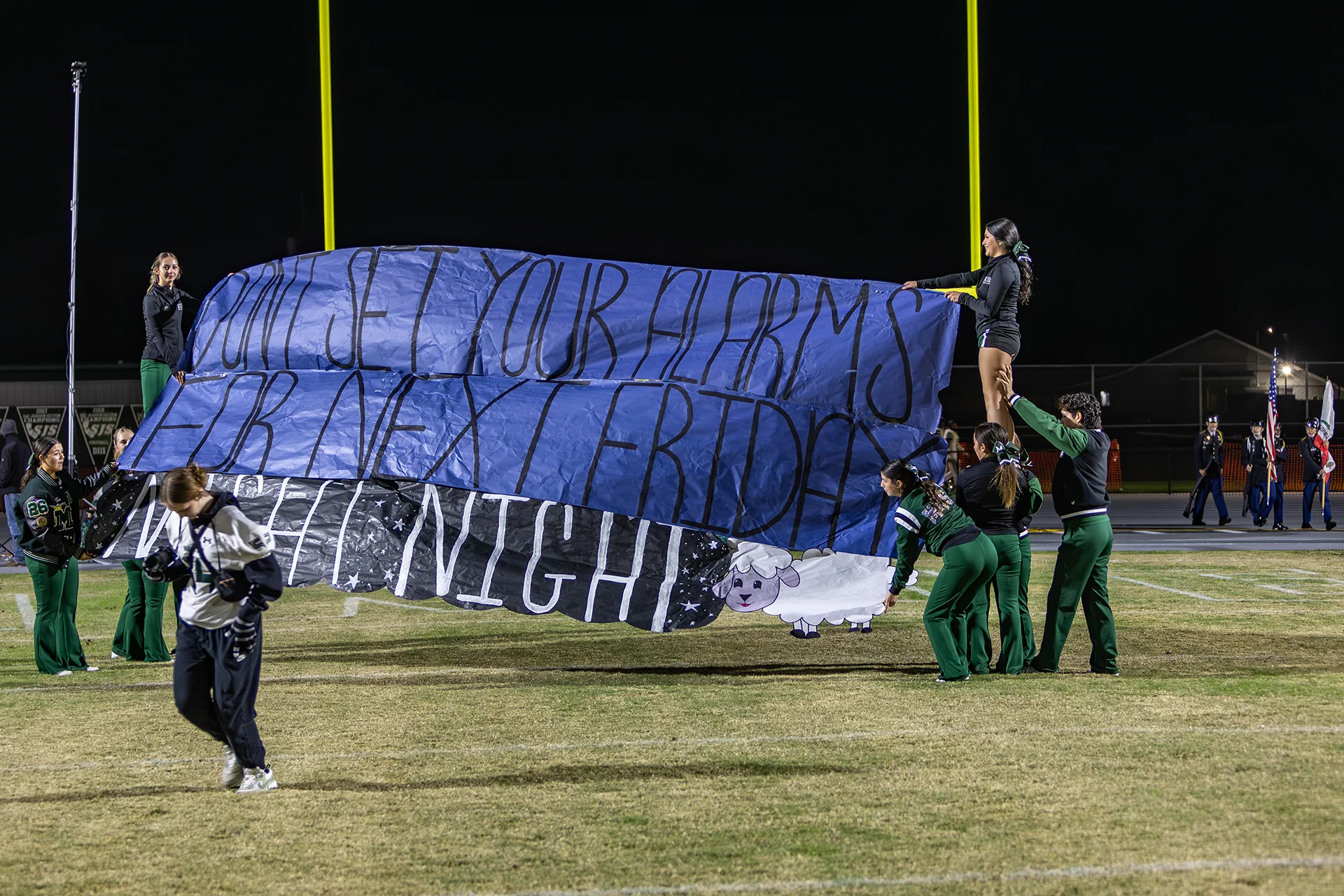 Students prepare a spirit banner on the football field during a Friday night event at Manteca High School stadium.