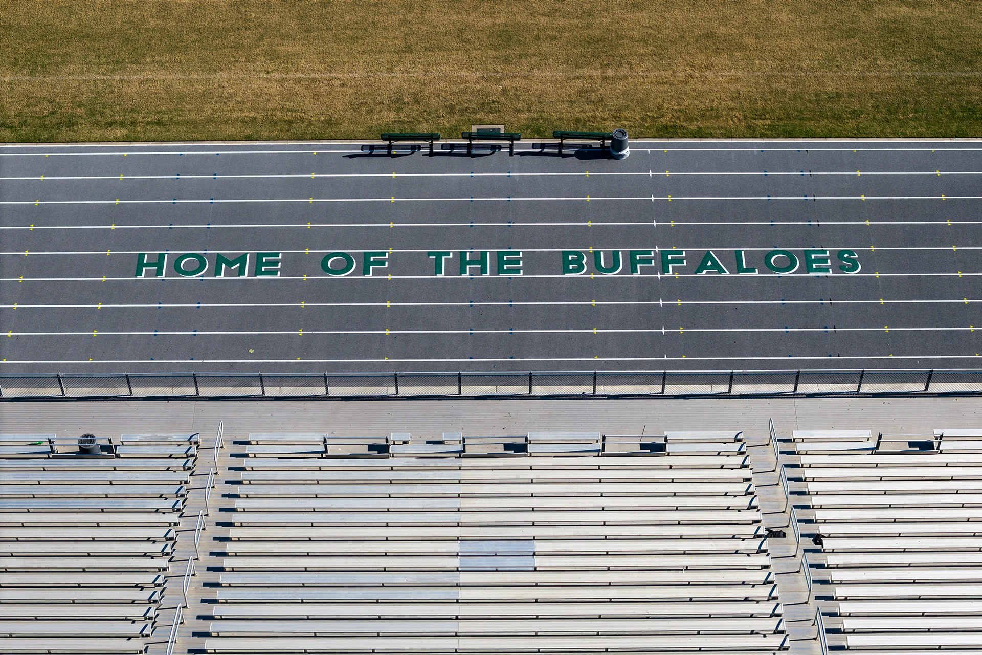 Aerial view of the running track and stadium seating at Manteca High School featuring Home of the Buffaloes lettering on the track surface.