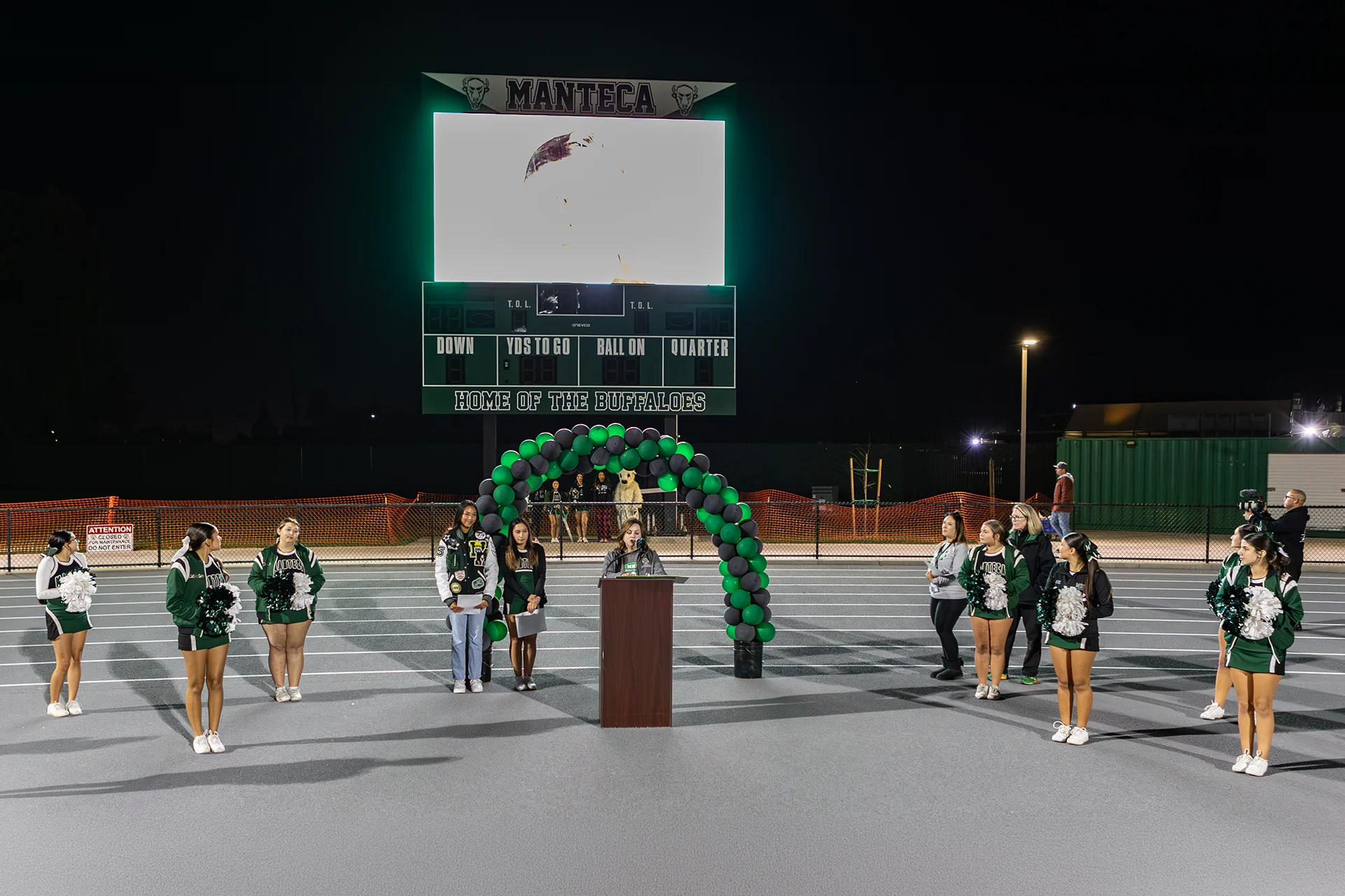 Students, cheerleaders, and staff gather on the renovated track during a dedication ceremony at Manteca High School stadium.