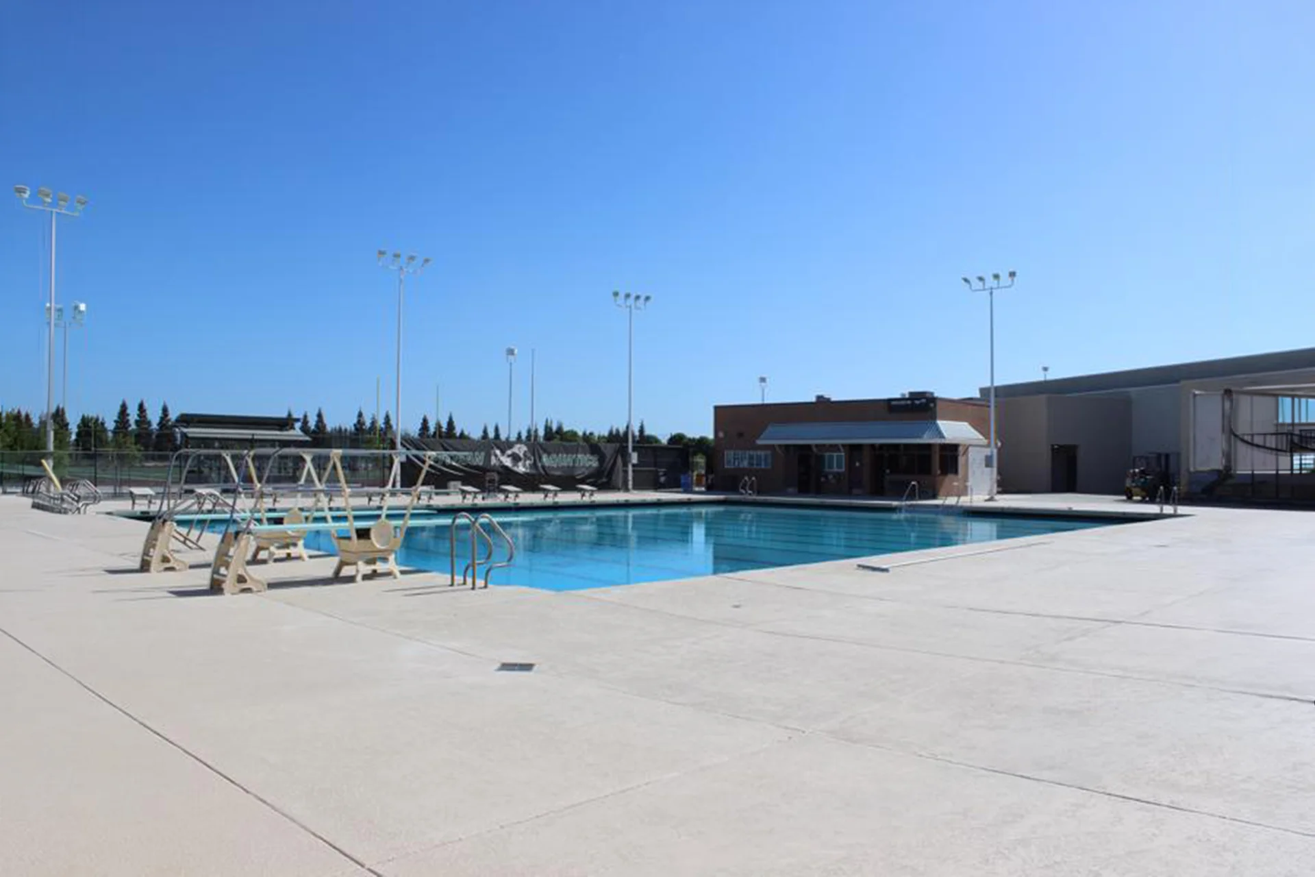 Outdoor swimming pool and deck area at Pitman High School’s aquatics center on a clear sunny day.