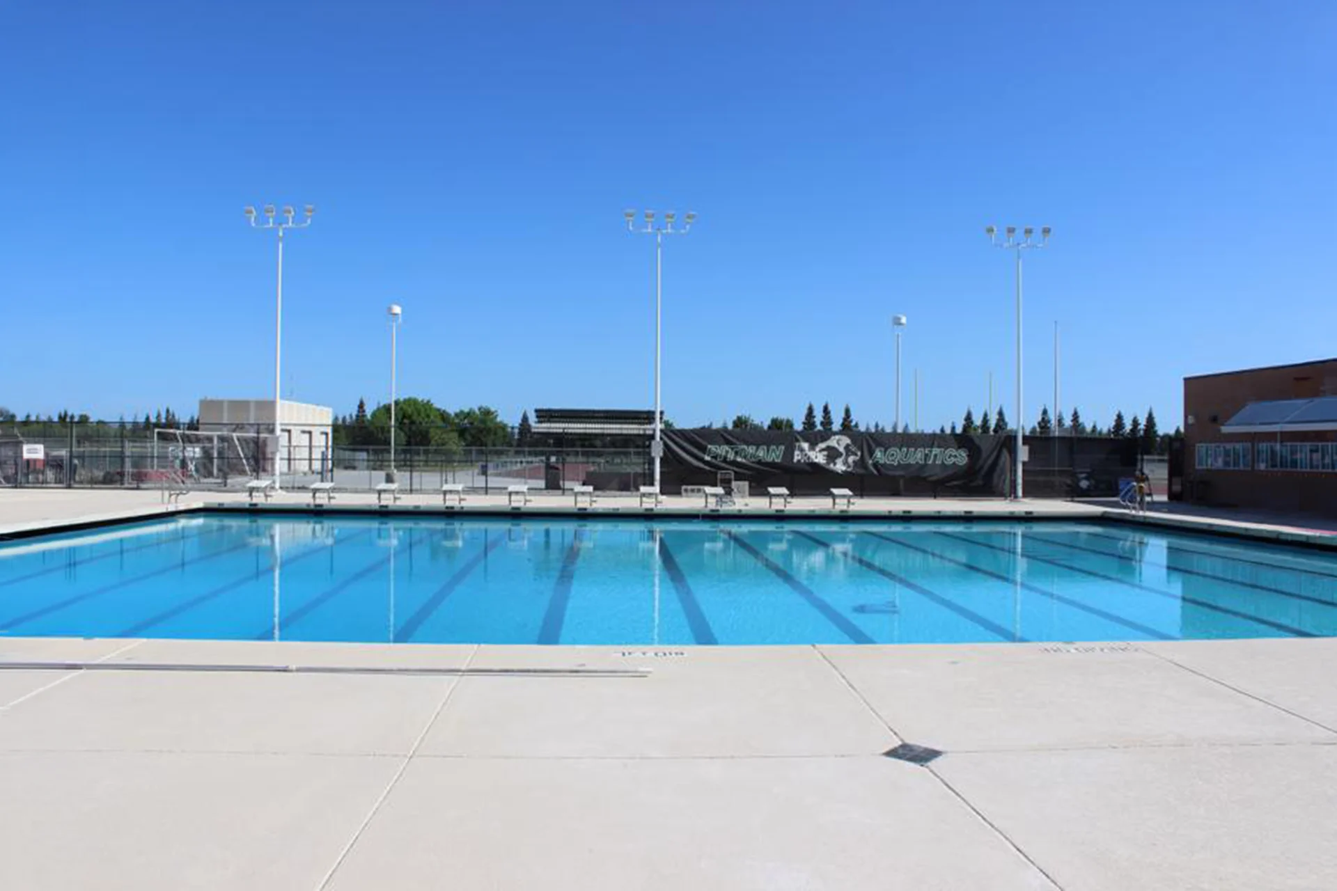 Competition swimming pool at Pitman High School’s aquatics facility featuring marked swim lanes and surrounding deck space.
