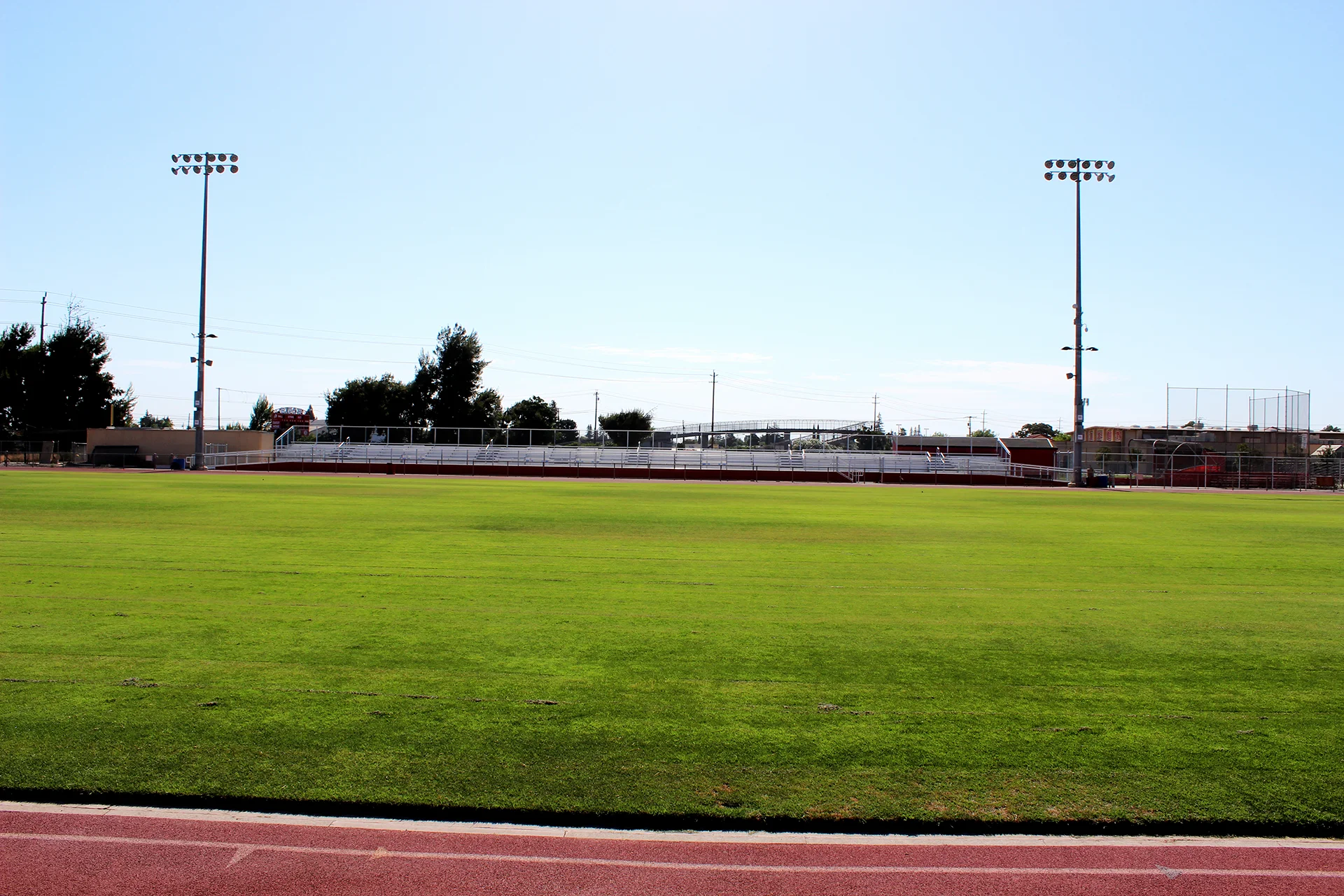 Wide view of Ripon High School’s athletic field, running track, stadium bleachers, and field lighting on a clear day.