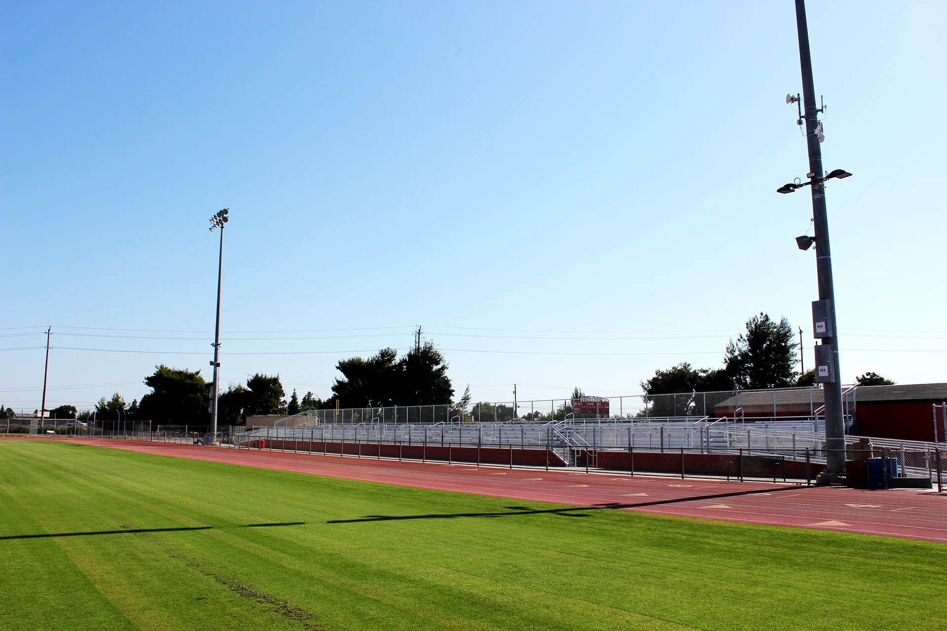 Ripon High School stadium bleachers, running track, and field lighting viewed from the athletic field on a clear sunny day.