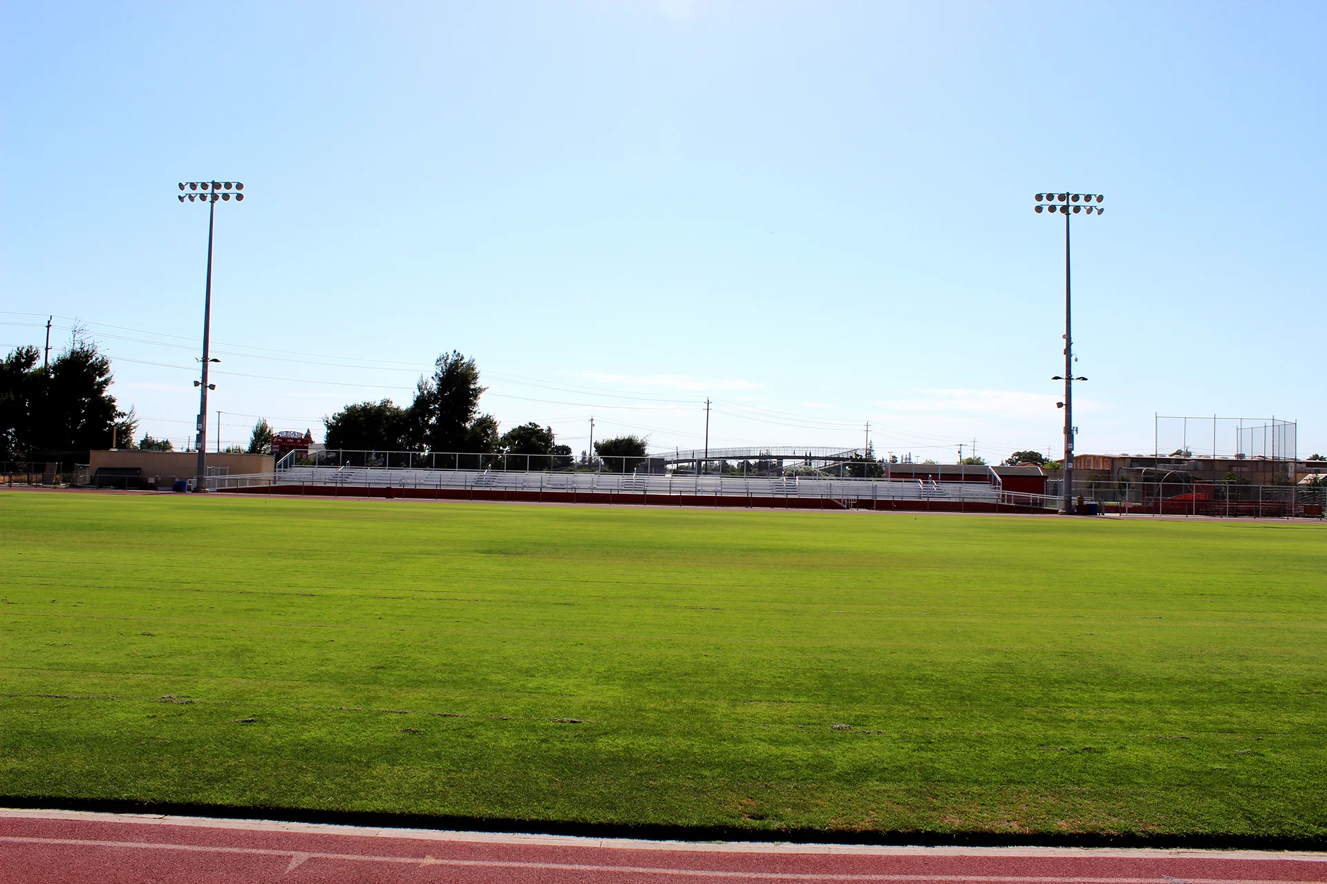 Wide view of Ripon High School’s athletic field, stadium bleachers, and field lighting surrounded by the running track on a clear day.