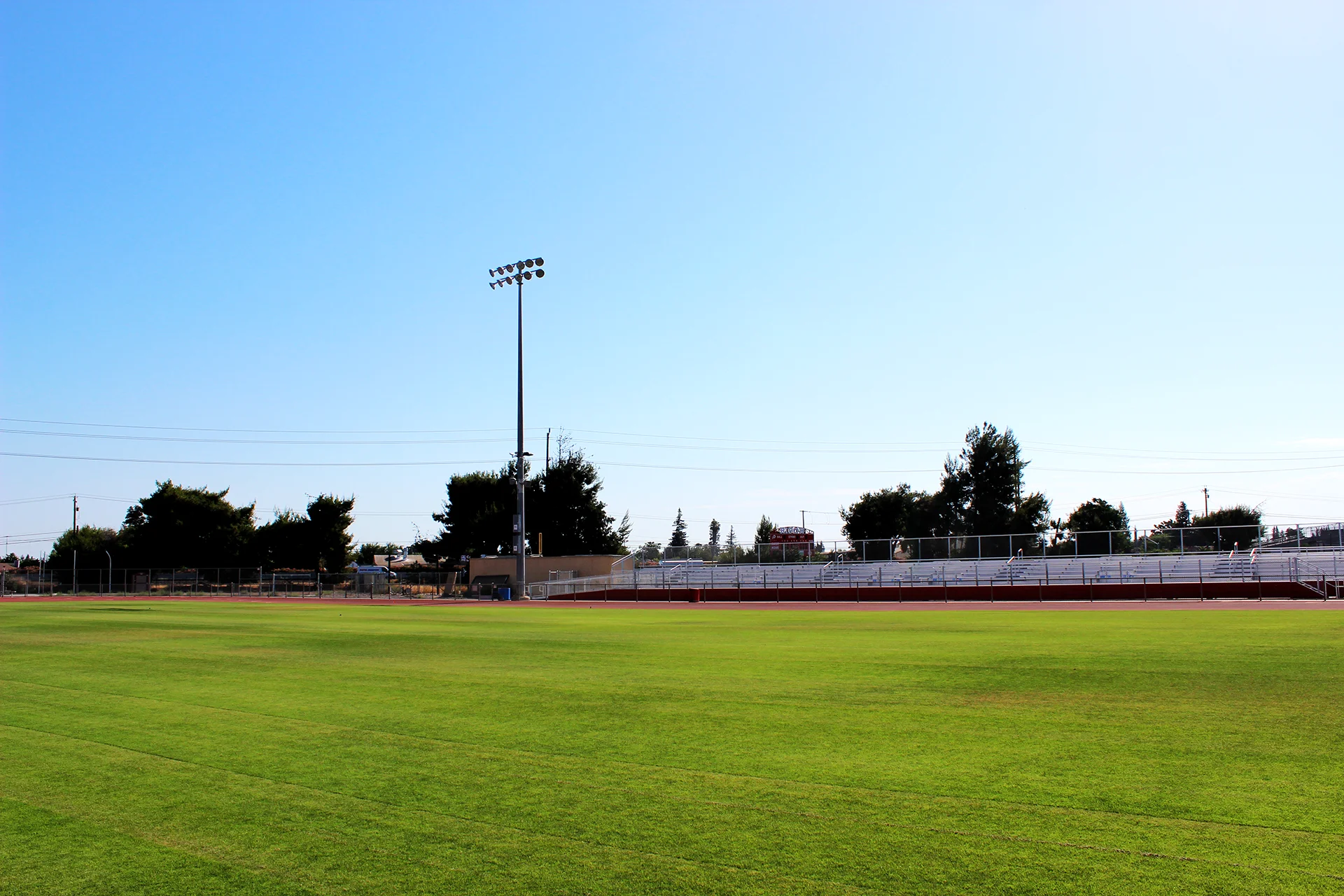 Ripon High School athletic field with stadium bleachers and field lighting visible across the running track on a clear day.