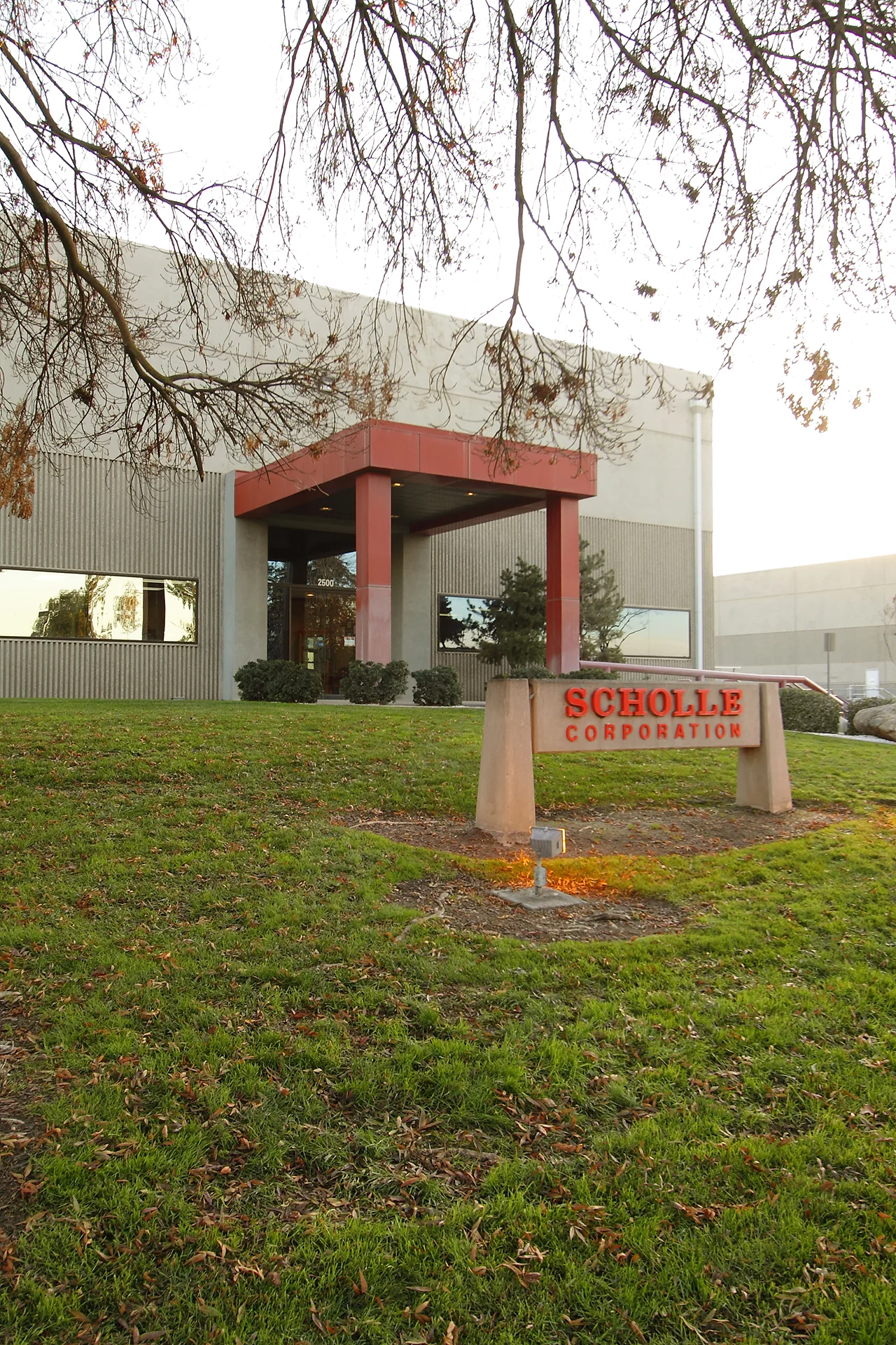 Front entrance of the Scholle Packaging corporate headquarters featuring the company monument sign, landscaped lawn, and modern industrial office building.