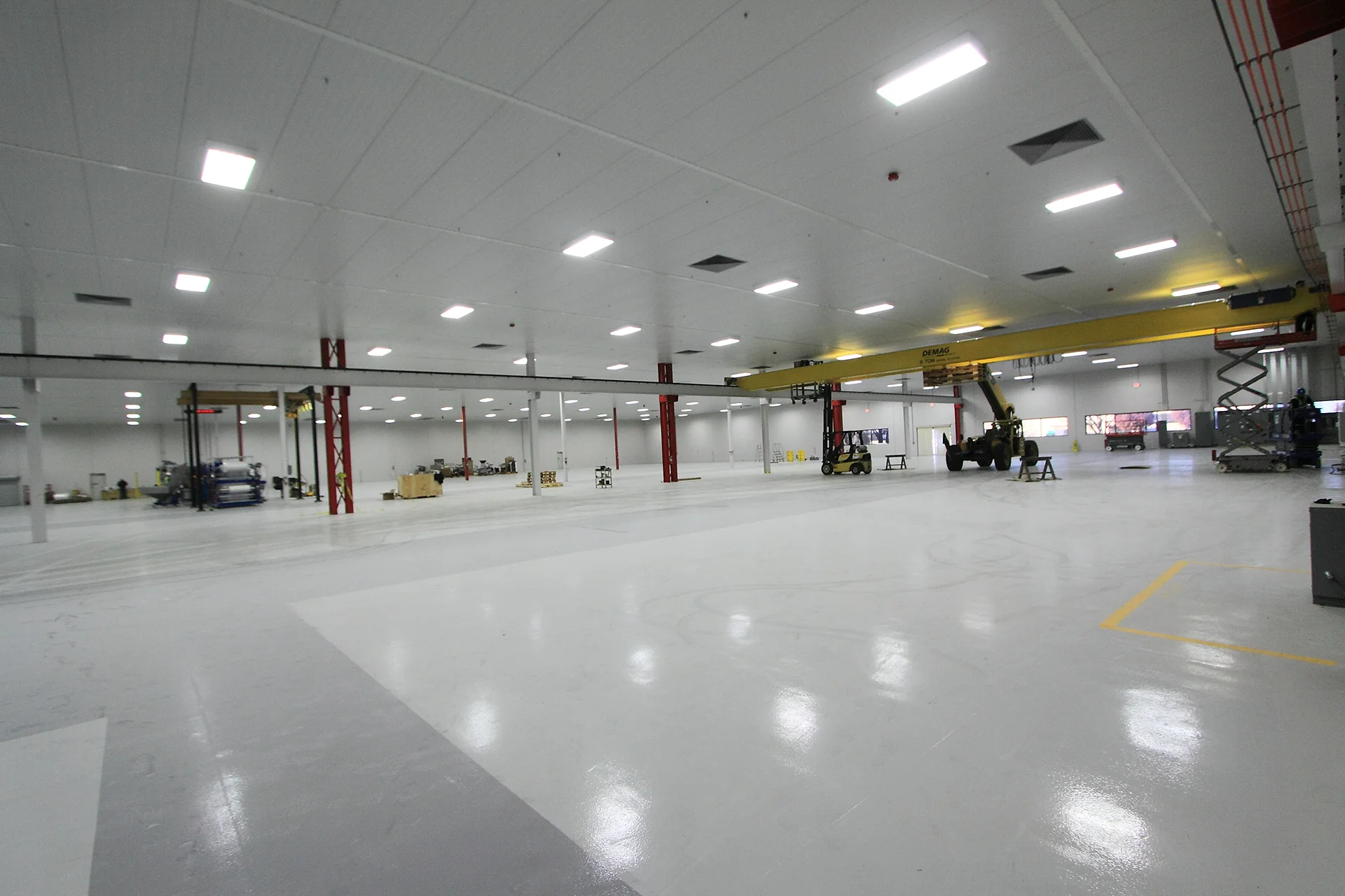 Spacious Scholle Packaging manufacturing facility featuring an open production floor, overhead crane system, industrial equipment, and high-bay lighting.