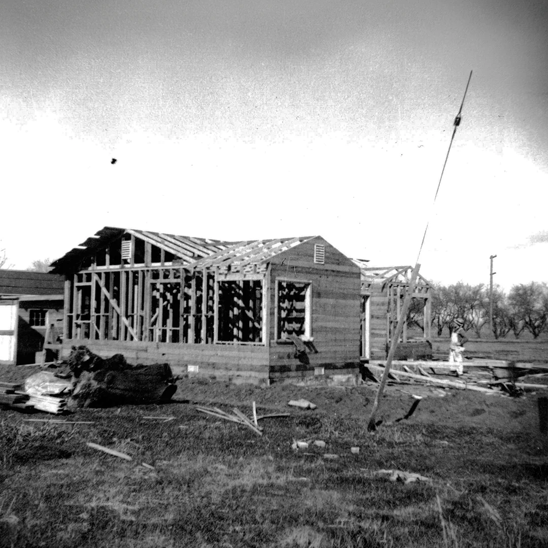First C.T. Brayton & Sons Construction Project Underway 1946 Historic black-and-white photograph showing the first C.T. Brayton & Sons residential construction project in 1946 with the home's wood framing in progress near the company's original office.