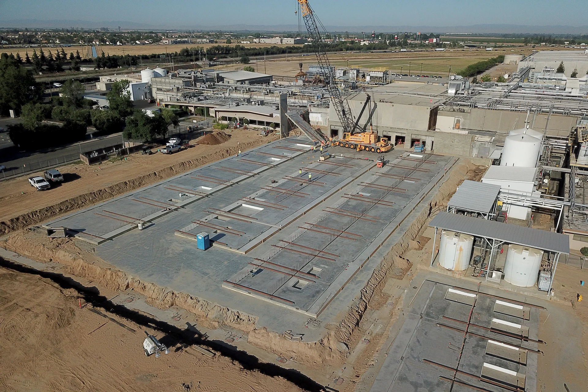 Aerial view of the Foster Farms Livingston Plant Expansion showing concrete foundations under construction, crane operations, and active industrial facility expansion.