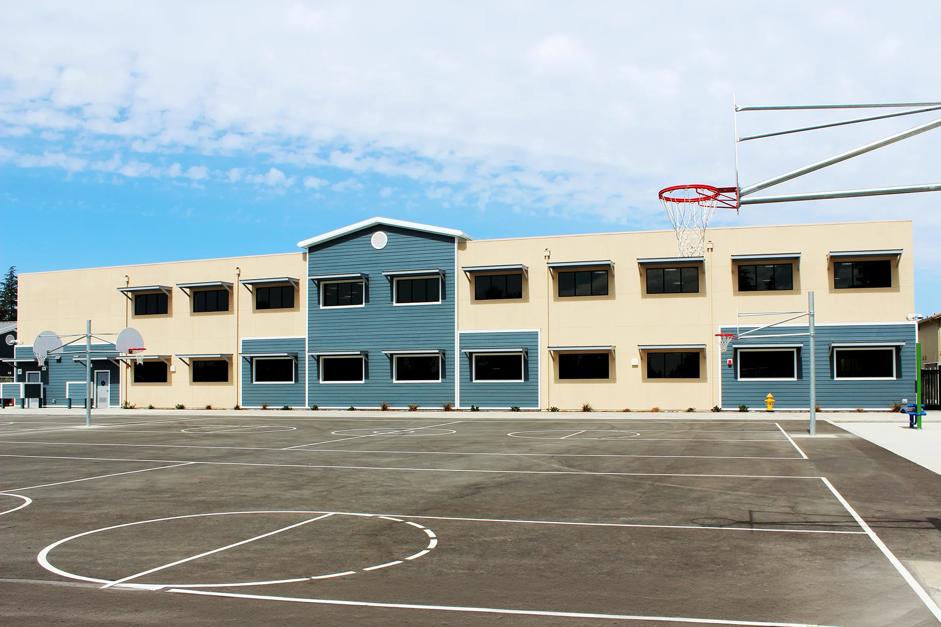 Classroom building at Quail Lakes Elementary School overlooking outdoor basketball courts, featuring modern educational facilities, large windows, and student recreation space.