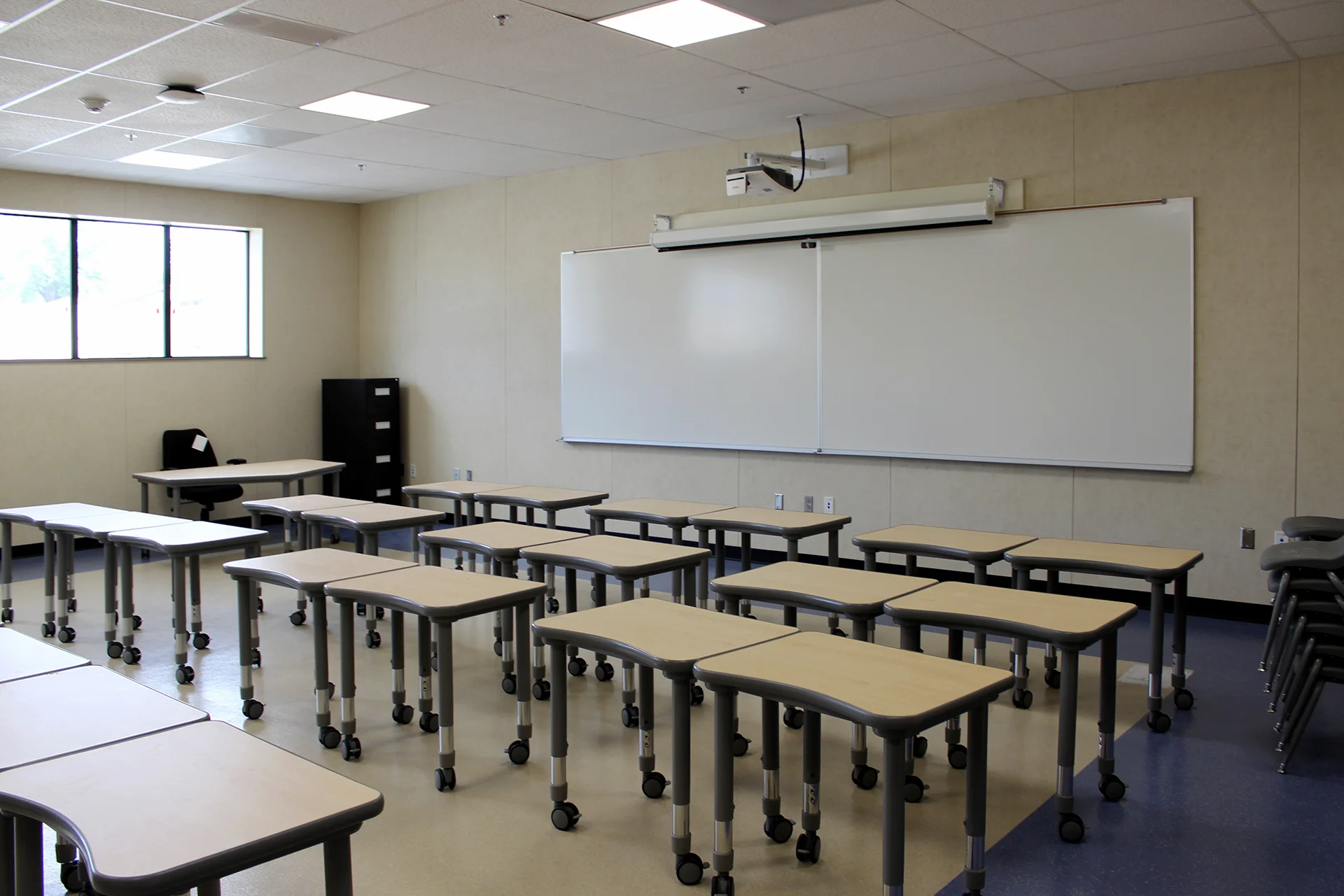 Modern classroom at Quail Lakes Elementary School featuring flexible student desks, interactive whiteboard, ceiling-mounted projector, and collaborative learning environment.