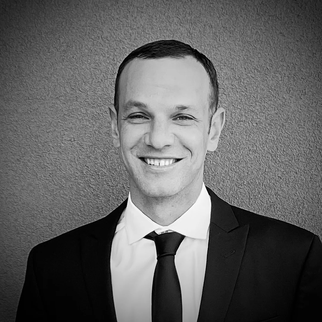 Ross Brayton Leadership Portrait Professional black-and-white portrait of Ross Brayton wearing a suit and tie, smiling toward the camera against a textured background.