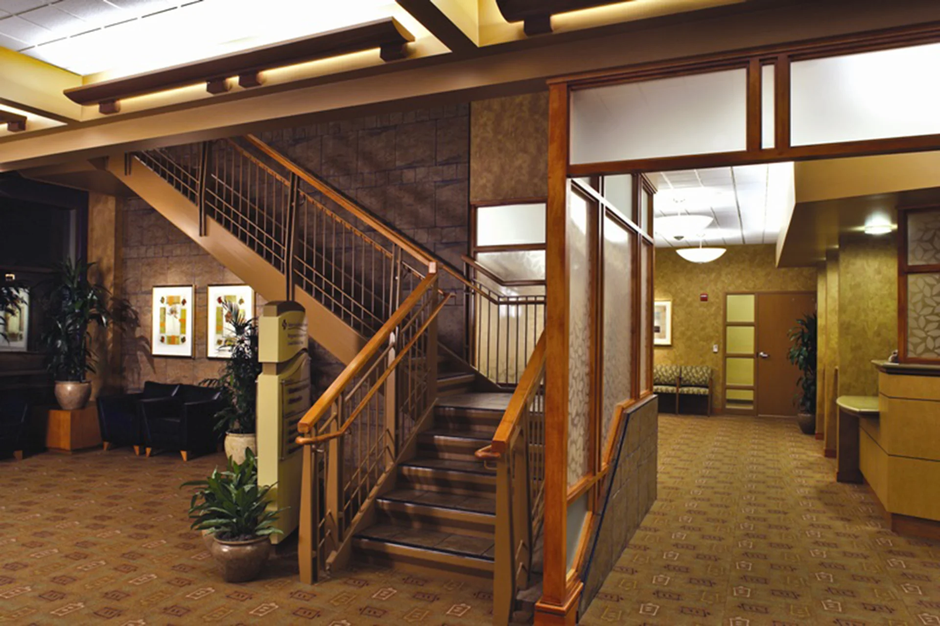 Interior lobby of the Sutter Gould Briggsmore Specialty Center featuring a central staircase, patient reception areas, warm architectural finishes, and a welcoming healthcare environment designed for patient comfort.