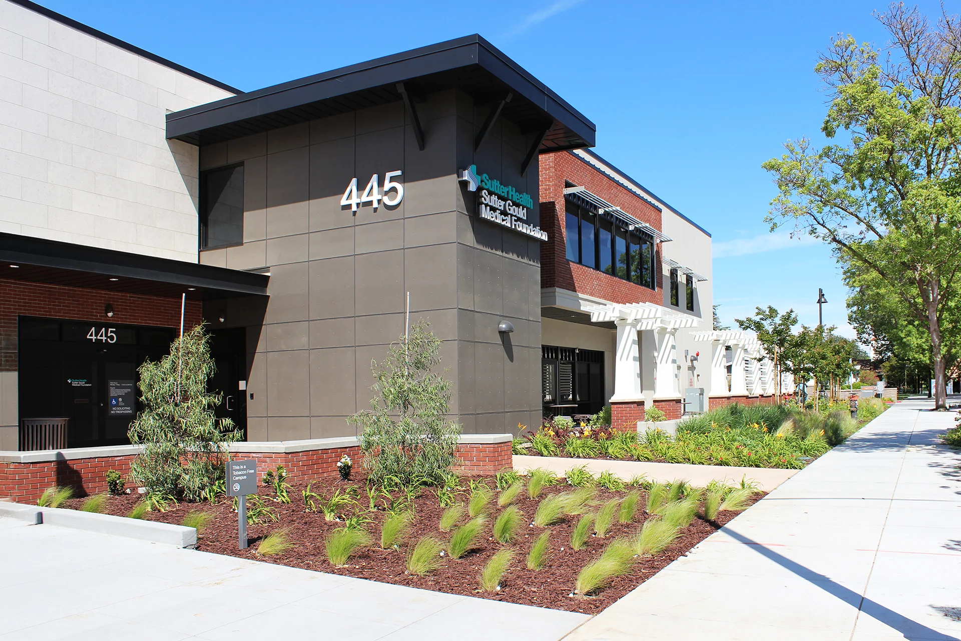Exterior entrance of the Sutter Gould Tracy Medical Office Building featuring contemporary healthcare architecture, landscaped pedestrian walkways, accessible entrances, and the Sutter Gould Medical Foundation campus.