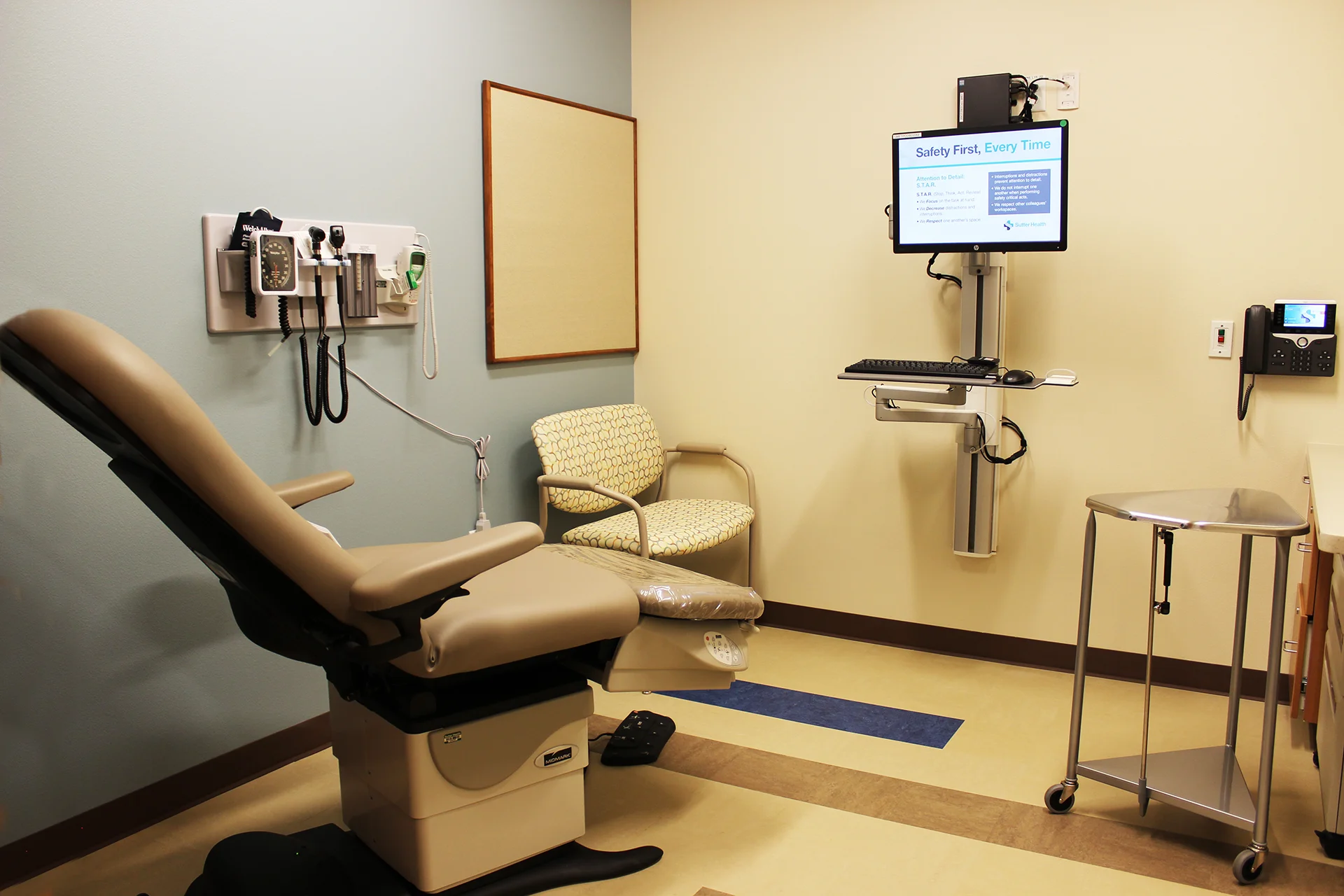 Patient examination room inside the Sutter Gould Tracy Medical Office Building featuring a medical exam table, diagnostic wall equipment, electronic health record workstation, and a modern clinical care environment.