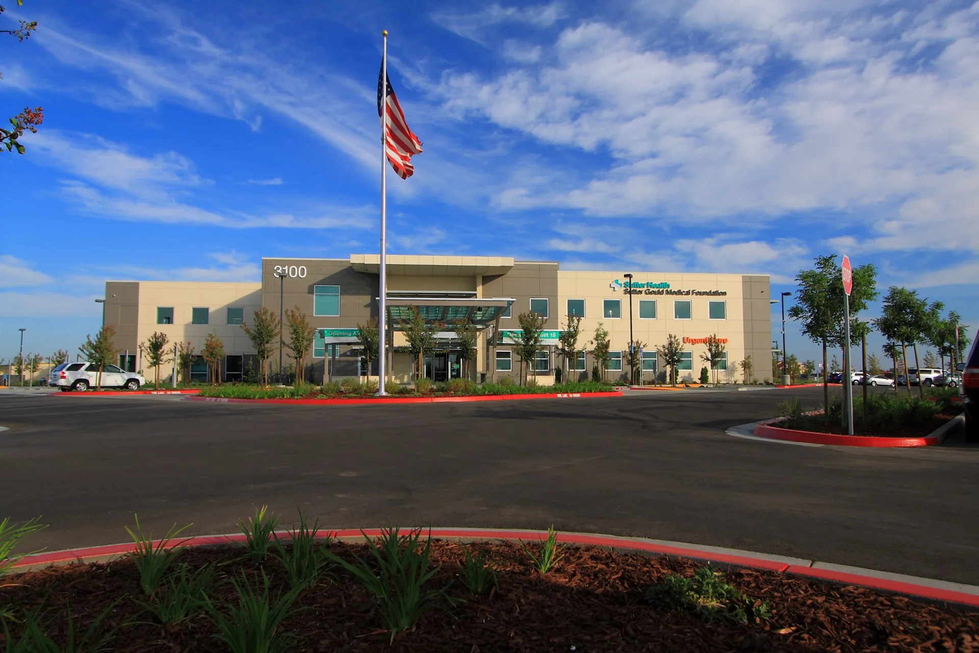 Wide view of the Sutter Gould Turlock Medical Office Building featuring the main entrance, landscaped healthcare campus, American flag, accessible parking, and modern outpatient medical facility.