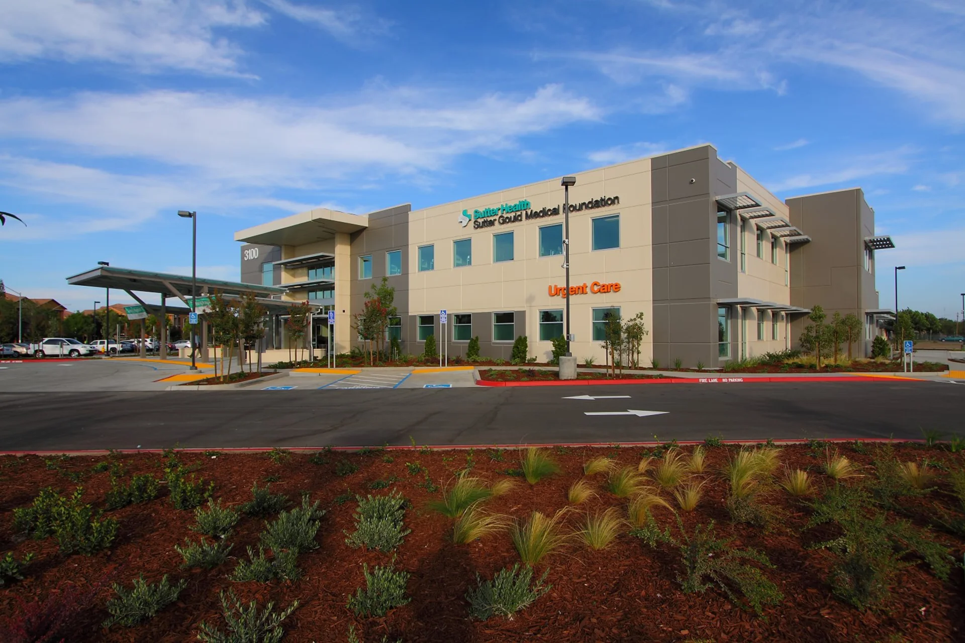Exterior view of the Sutter Gould Turlock Medical Office Building featuring the Urgent Care wing, modern medical office architecture, landscaped grounds, accessible parking, and patient drop-off area.