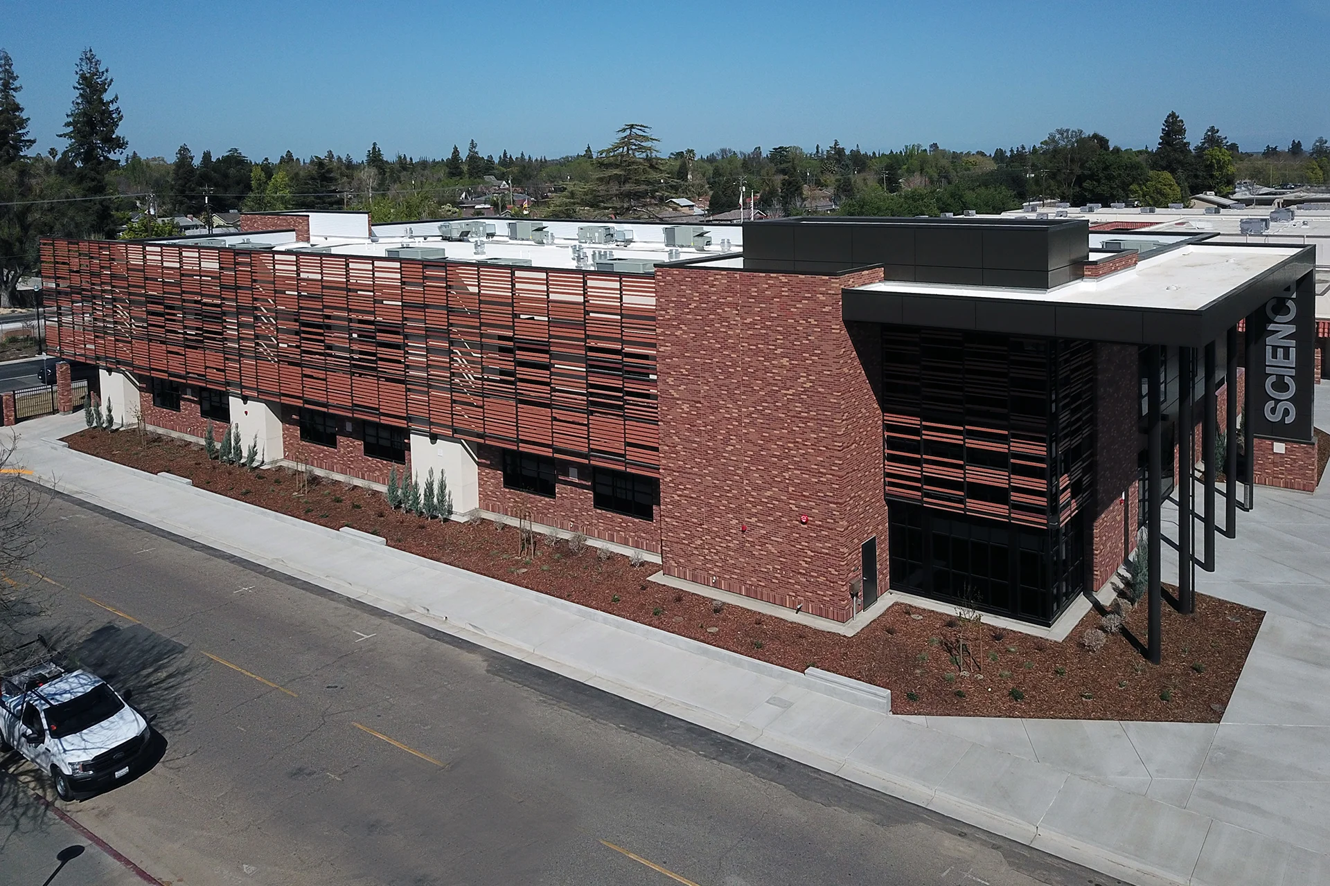 Aerial view of the Turlock High School Science Building showcasing modern brick architecture, sunshade façade, landscaped grounds, and dedicated STEM education facilities on campus.