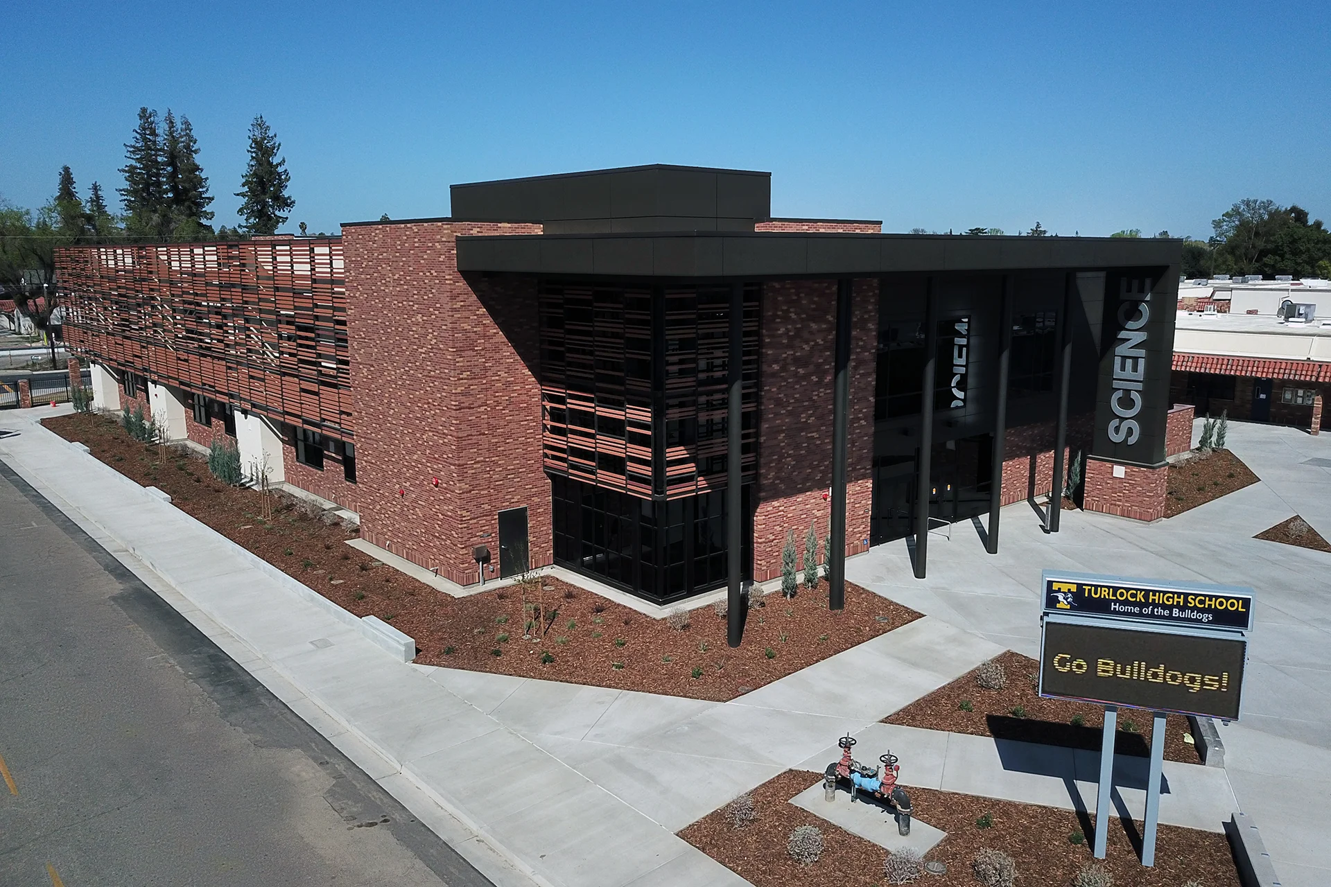 Aerial campus view of the Turlock High School Science Building featuring contemporary brick architecture, solar shading elements, landscaped entrances, and a dedicated STEM education facility.