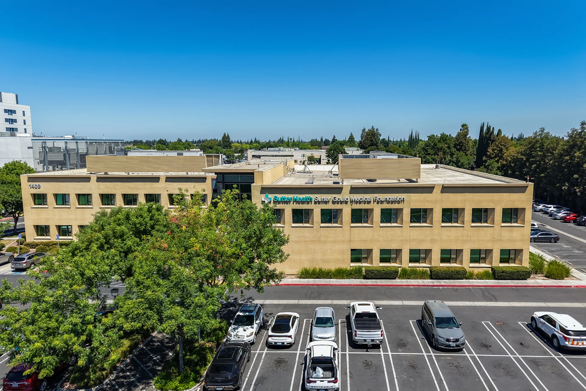 Exterior view of the Sutter Gould Briggsmore Specialty Center featuring a contemporary medical office building, glass entrance, landscaped campus, patient parking, and illuminated healthcare facility at dusk.