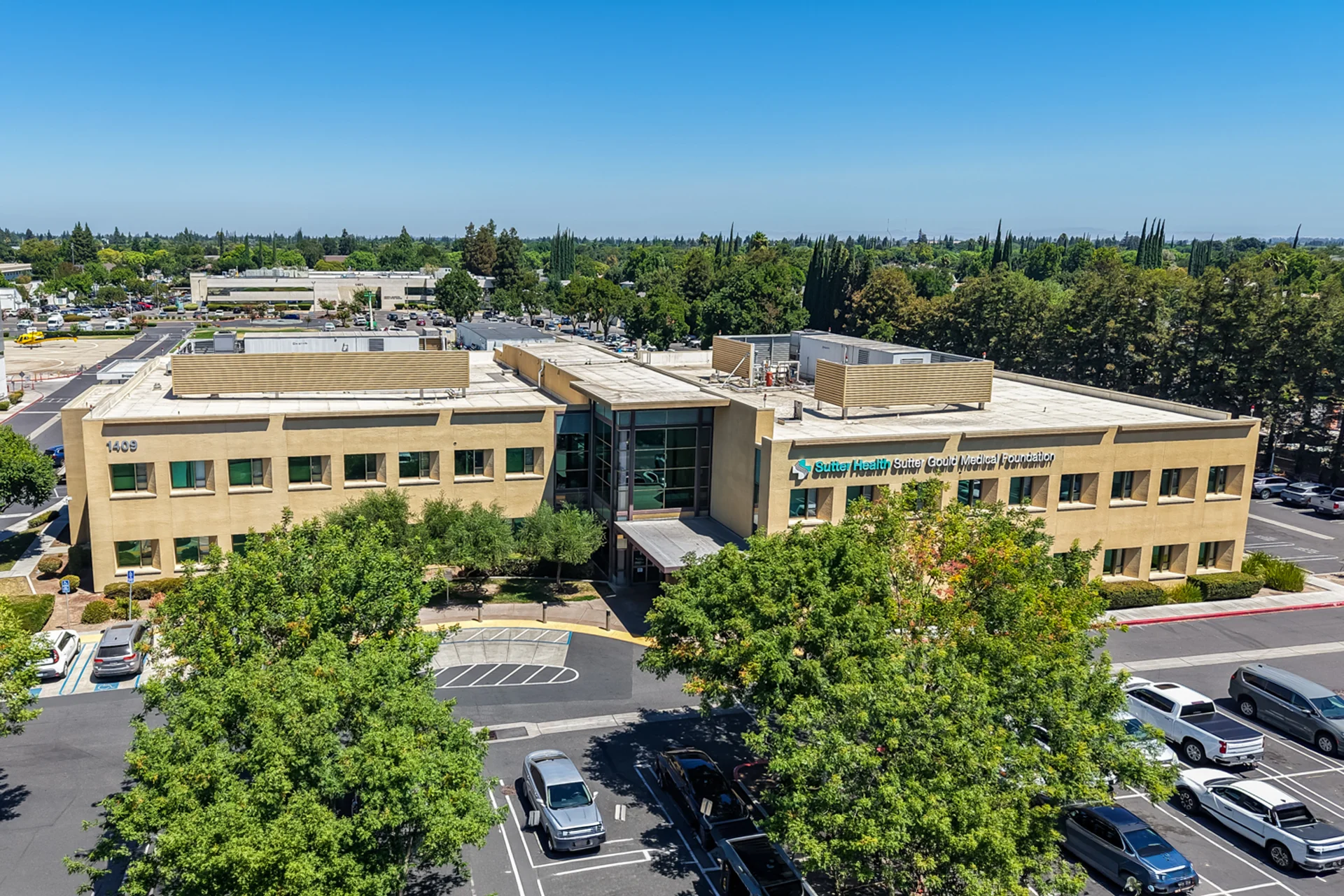 Elevated front view of the Sutter Gould Briggsmore Specialty Center featuring the main entrance, contemporary medical office architecture, landscaped grounds, and patient parking in Modesto, California.