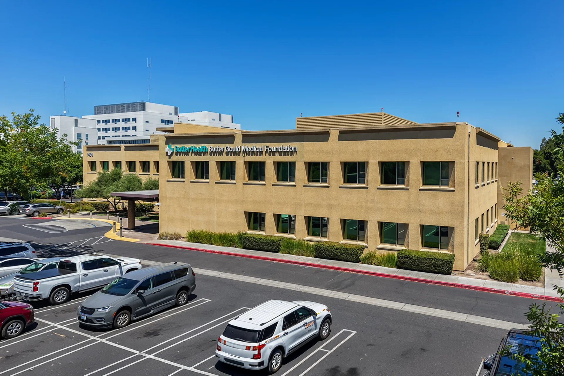 Elevated exterior view of the Sutter Gould Briggsmore Specialty Center featuring the medical office building, patient parking, covered entrance, and landscaped outpatient healthcare campus in Modesto, California.