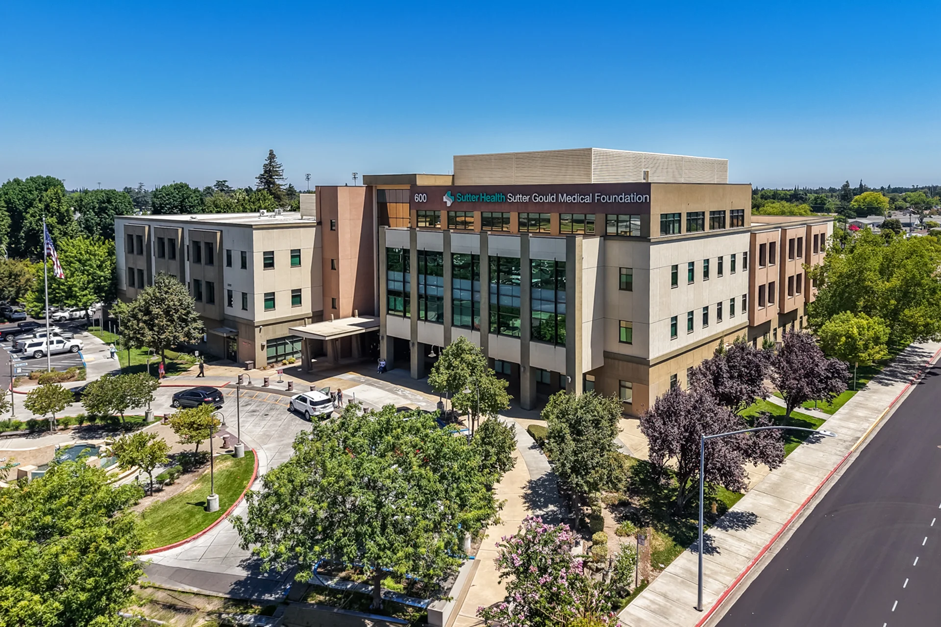 Aerial view of the Sutter Gould Coffee Road Medical Office Building showcasing the multi-story outpatient healthcare campus, landscaped grounds, patient drop-off area, and surrounding neighborhood in Modesto, California.