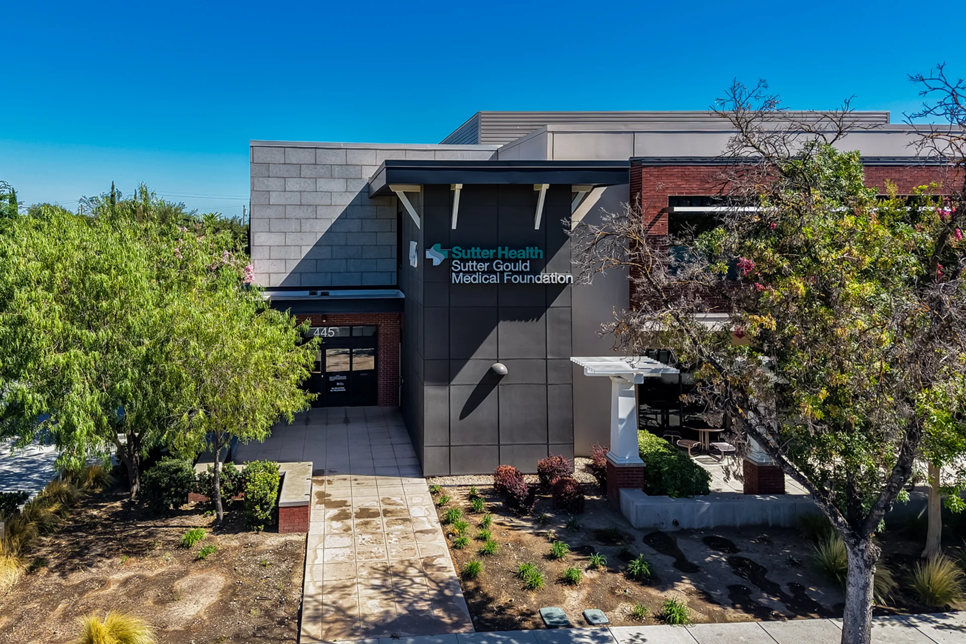 Exterior entrance of the Sutter Gould Tracy Medical Office Building featuring contemporary healthcare architecture, landscaped pedestrian walkways, accessible entrances, and the Sutter Gould Medical Foundation campus.